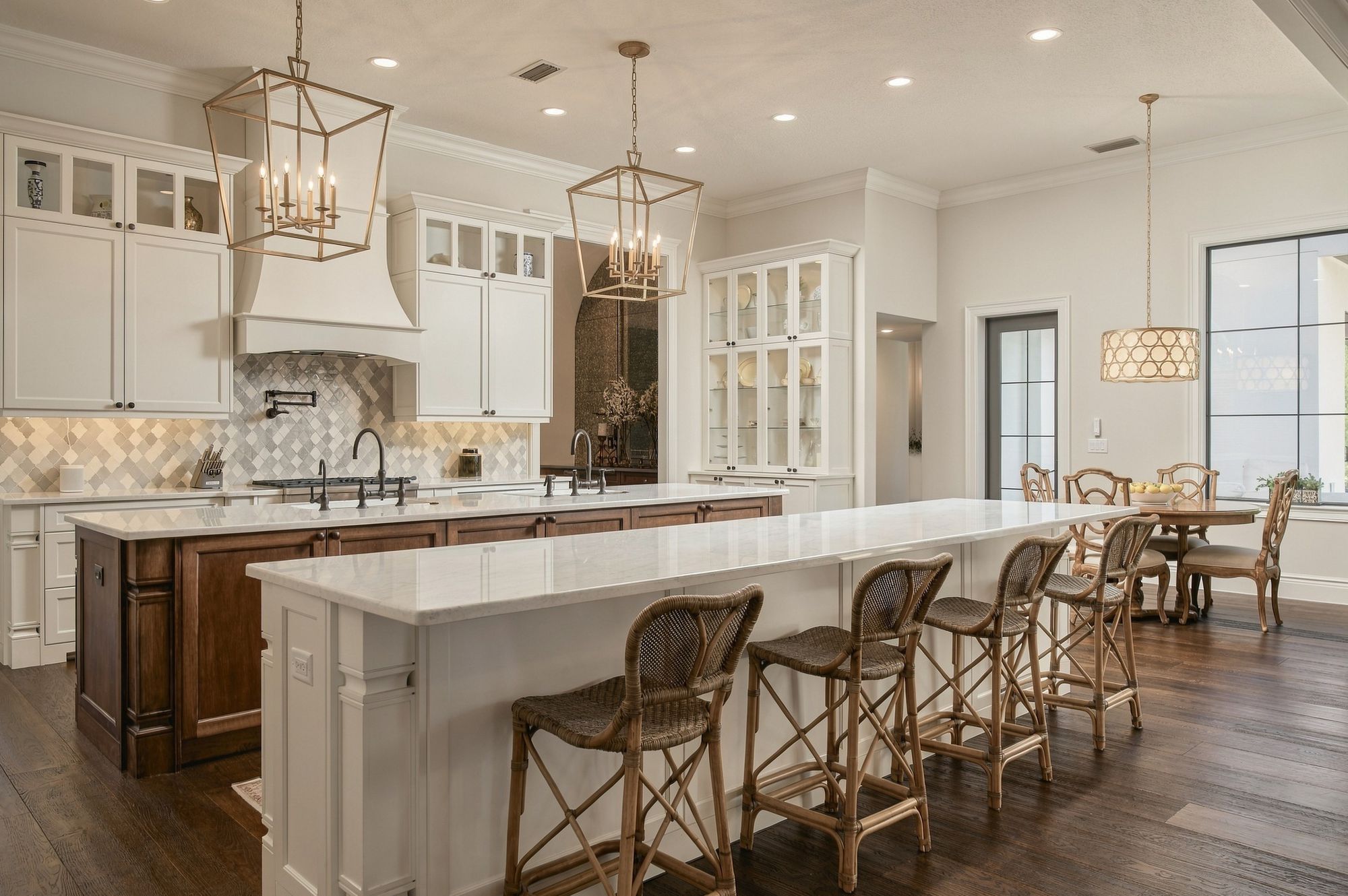 Classic white kitchen with lantern pendants and a long island with rattan stools
